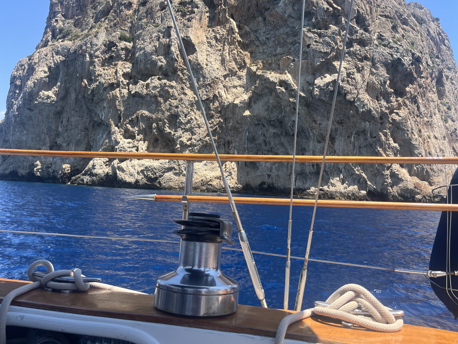 The furler and rigging aboard Gran Blau against a dramatic rocky coastline