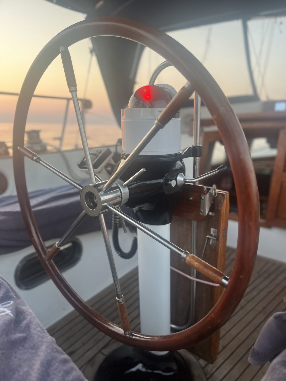 The wheel and compass aboard Gran Blau at dusk